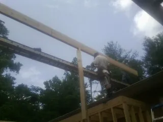 Carpenter setting a ridge beam over a new addition frame — Ice Dam Removal by Roofing Brothers in Hines