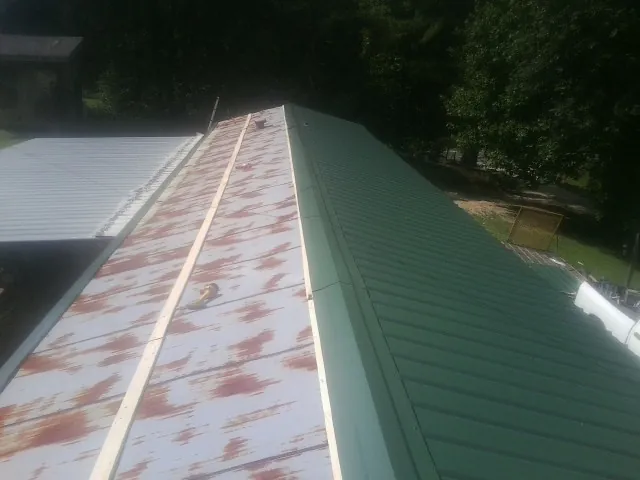 Old rusted panels beside newly installed green metal roofing — Wind Damage Roof Repair by Roofing Brothers in Hines