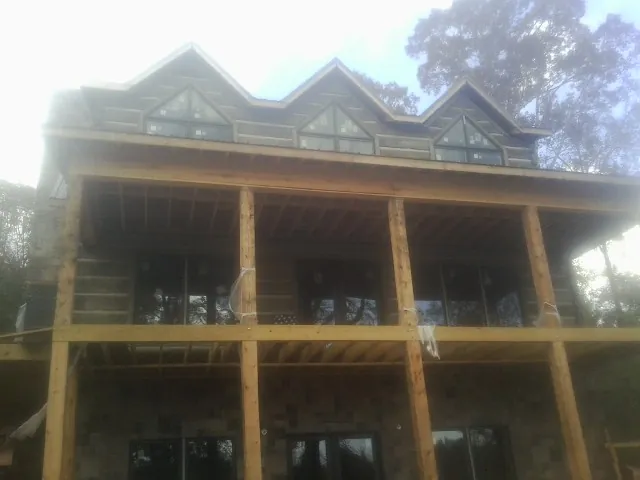 Dormers and porch framing on a large log home under construction — Roof Coating work by our crew in Hines