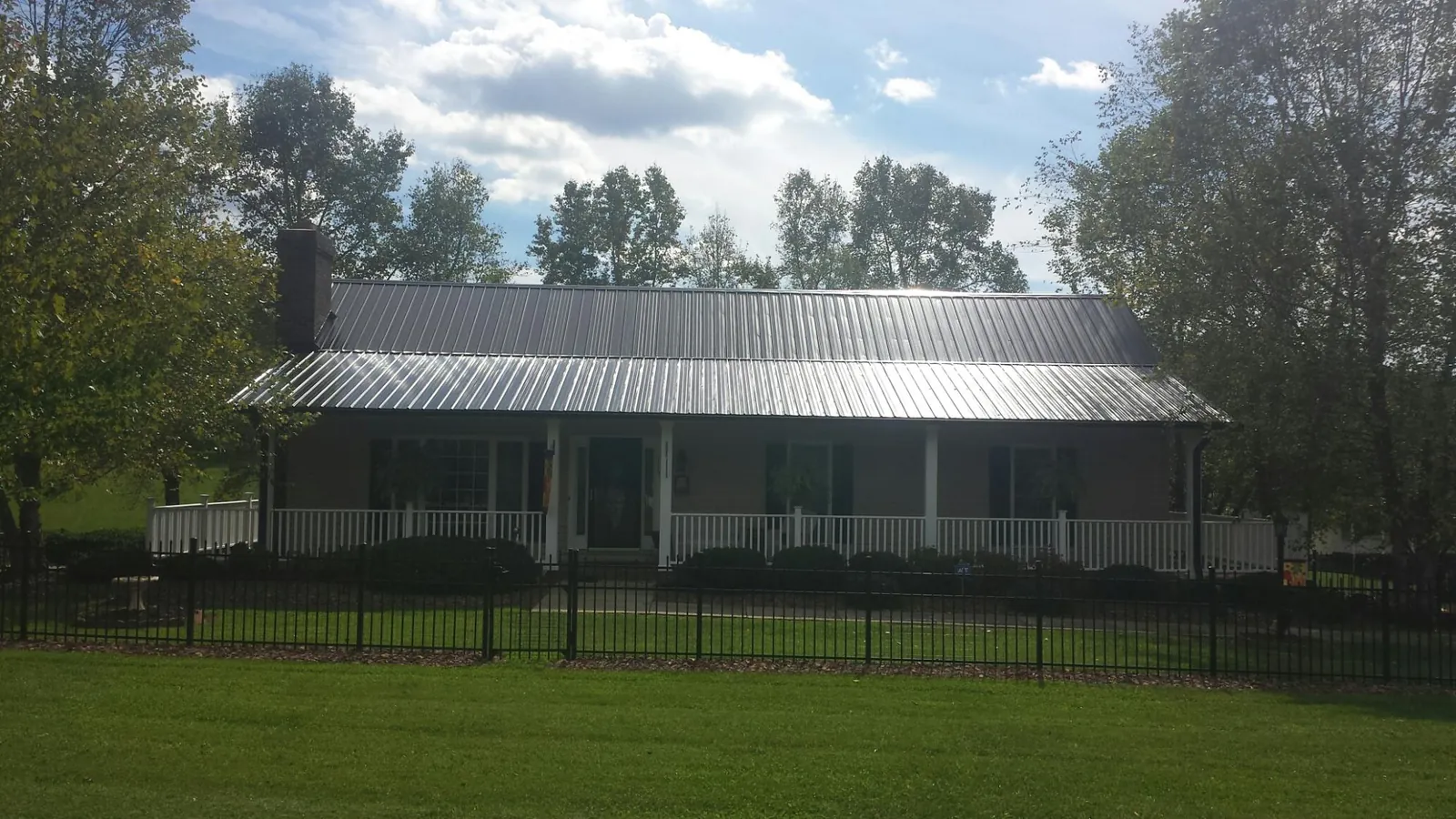 Gray metal roof on a brick ranch with a full width front porch — Gutter Guard Installation work by our crew in Hines