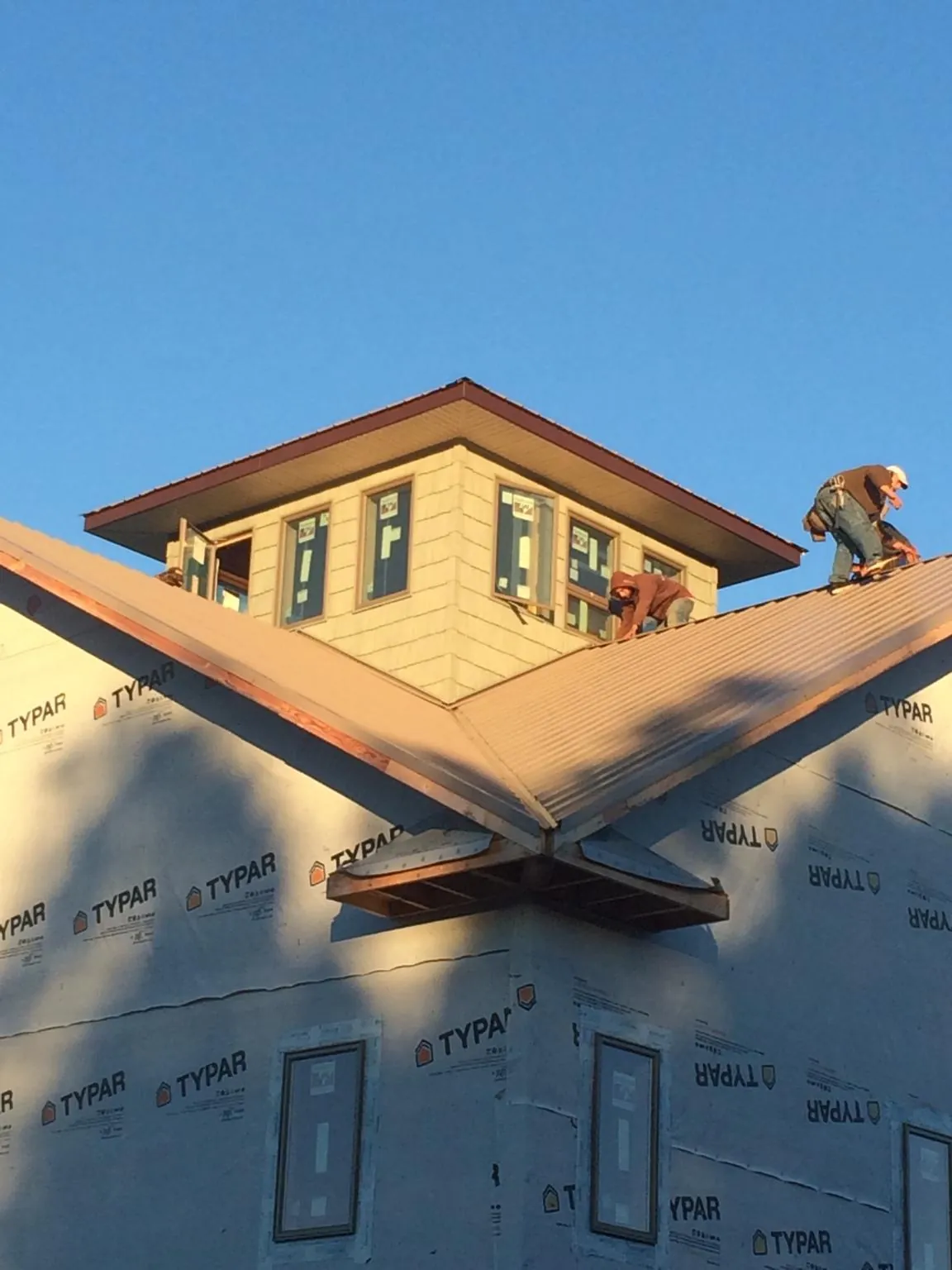 Roofers working around a rooftop cupola on a new metal roof at sunset — Roof Waterproofing in Hines by Roofing Brothers